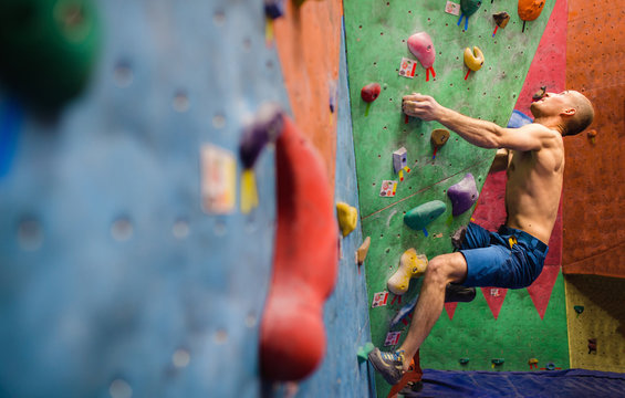muscular and fit man exercise in free mountain climbing on indoor practice artificial bouldering wall with copy text space