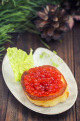 healthy appetizer : sandwich with red caviar on white china plate. Wooden background. Top view. Close-up