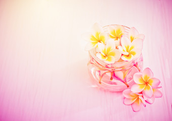 White plumeria flowers in vase glass on wood table add pink color filter