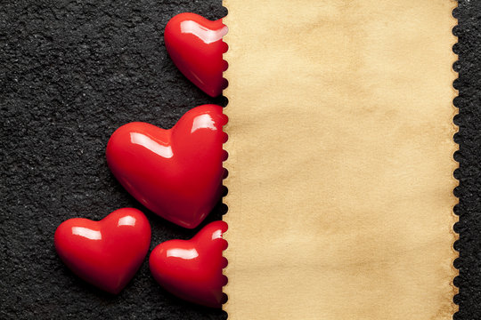 Blank paper sheet and red hearts on black background