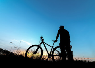 Fototapeta na wymiar Silhouette man with mountain bicycle at sunset
