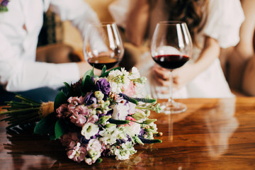 Wedding bouquet near to glass of red wine