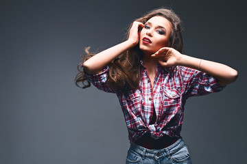 Portrait of a young beautiful caucasian white girl wearing a plaid shirt and jeans on grey background