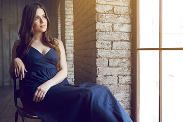 Fototapeta premium Portrait of young woman with long hair beside window.