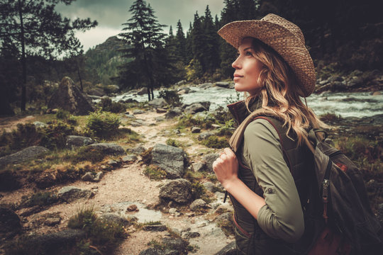 Beautiful woman hiker enjoying amazing landscapes near wild mountain river