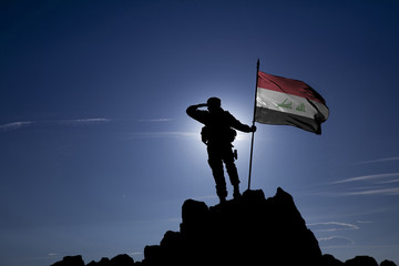 Soldier on top of the mountain with the Iraqi flag - obrazy, fototapety, plakaty