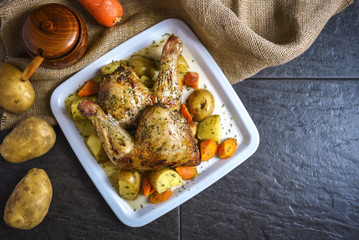 Roasted chicken with potato, carrot and herbs, top view