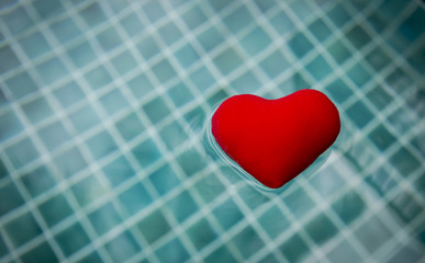 Red heart floating on swimming pool water