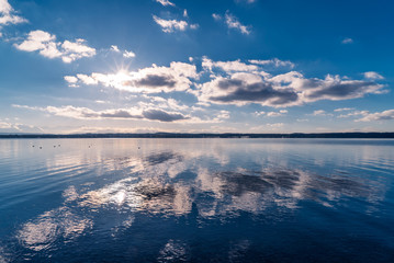 Starnberger See mit Alpenblick, Sonnenschein und spiegelnden Wolken