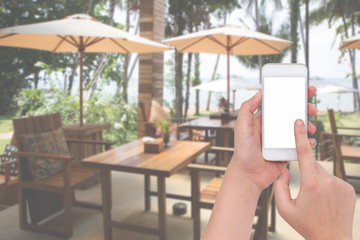 Female hand holding a phone on blur restaurant and sea backgroun