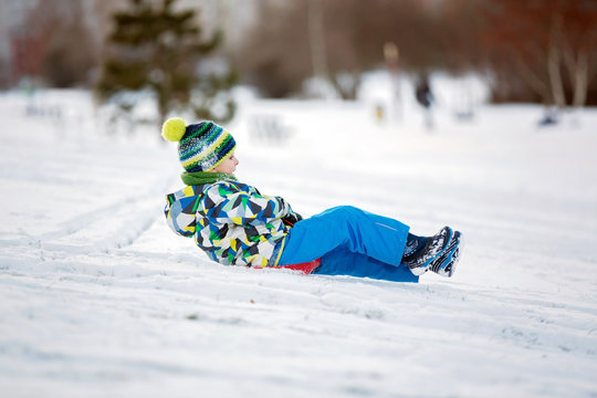 Cute child, boy, sliding with bob in the snow, wintertime