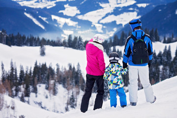 Fototapeta na wymiar Young happy family with one child, skiing in the mountains