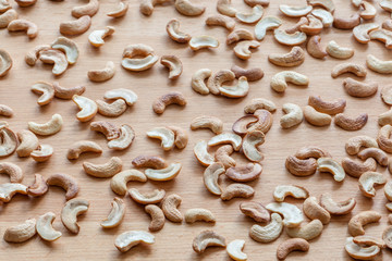 Roasted cashew nuts spread around wooden board.