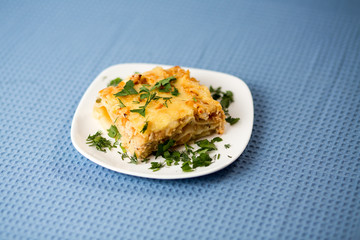 Lasagna with greens on a plate on a blue napkin, macaroni with chicken forcemeat