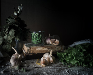 rustic still life, vintage. green peas, garlic, old books, flour on a wooden table. dark background