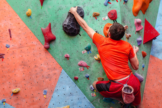 young caucasian amateur man rock climbing indoors at gym