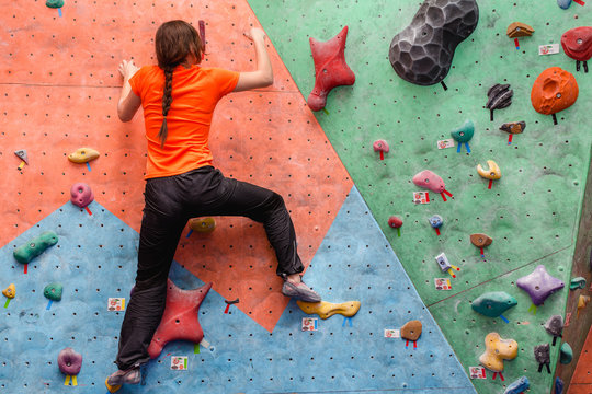 Young strength woman extreme bouldering in a modern rock climbing gym indoors