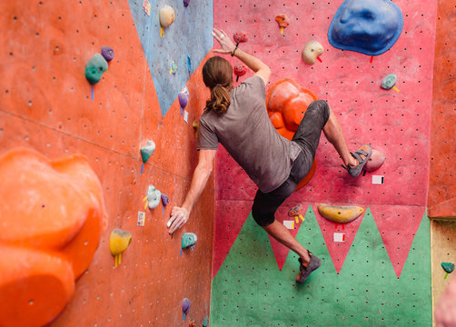 Sport man exercising on artificial climbing wall, modern leisure concept