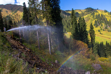 Woman are standing in the mountains near a water pipe with rainb