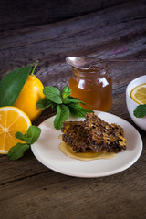 Honeycomb, honey in jar, green tea, lemon with leaf and mint on