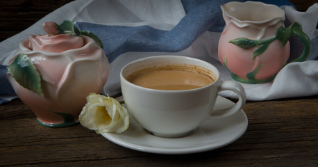 Cup of coffee with milk, red grapes, pink crockery and eustomas