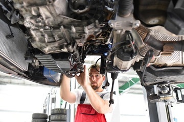 Automechaniker repariert defektes Fahrzeug auf der Hebebühne in einer Werkstatt 