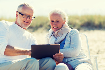 happy senior couple with tablet pc on summer beach