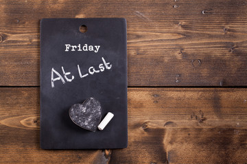 Finished the working week concept. Friday at last, notice on a chalk board with chalk and heart shaped eraser.