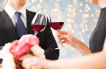 close up of couple clinking red wine glasses