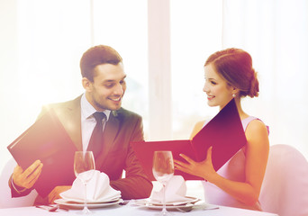 smiling couple with menus at restaurant