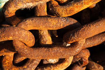 Big iron chains from an old ships anchor rusting by the harbor side close up