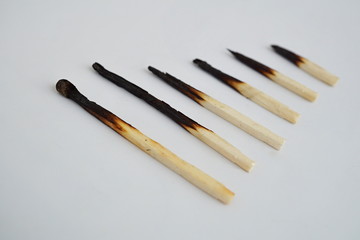 Conceptual set of burnt matches gradually arranged by stages of their incineration on white background 