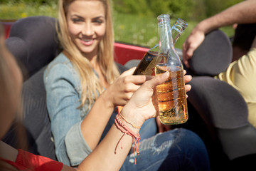 happy young women with drinks in convertible car