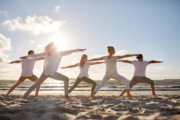 Fotobehang groep mensen die yoga-oefeningen maken op het strand © Syda Productions