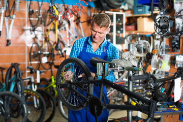 Fototapeta na wymiar seller in uniform repairing bicycle