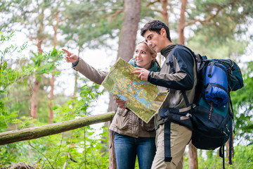 Junges Paar, Frau und Mann, beim Wandern suchen den richtigen Weg mit Wanderkarte