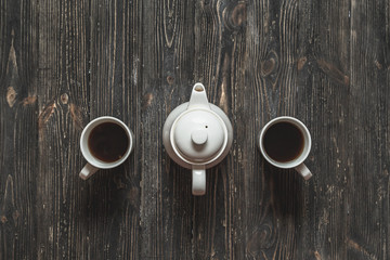 Tea set for the pair. Cups and teapot on black rustic table.