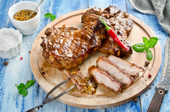 Grilled Steak on bone with knife and fork carving set on wooden