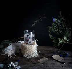 still life, vintage. a glass of mineral water and berries, books, bouquet on  wooden table. dark backgrounds. .
