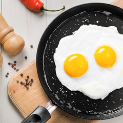 Fried eggs meal in a frying pan for delicious healthy breakfast. Traditional international breakfast food, top view.