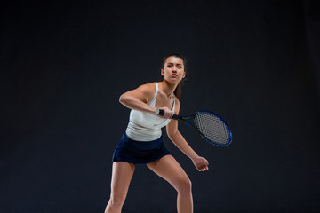 Portrait of beautiful girl tennis player with a racket on dark background