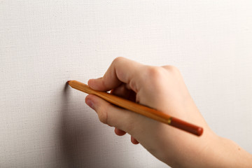 карандаш в руке подростка, рисующего на чистом холсте
