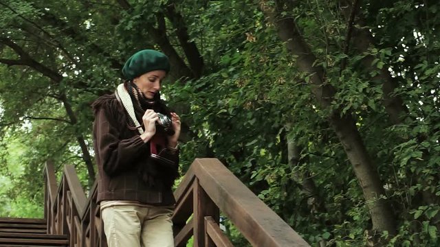 Young woman is taking photos on a old vintage film camera at the autumn park. HD