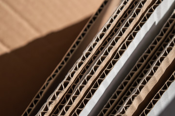 Texture of layered brown cardboard side. Folded cardboard boxes. Wavy paper texture on sunlight with copy space.