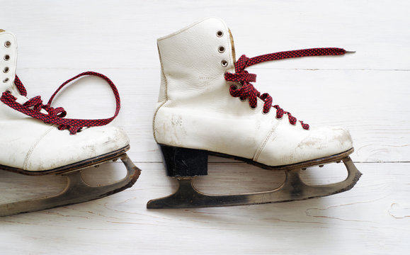 Old white skates for figure skating on a wooden surface