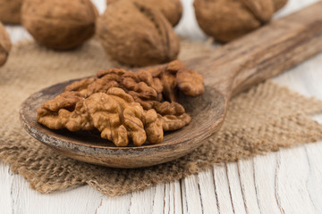 Walnuts in a wooden spoon and an old white wooden table.