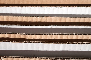 Obraz premium Texture of layered brown cardboard side. Folded cardboard boxes. Wavy paper texture on sunlight with copy space.