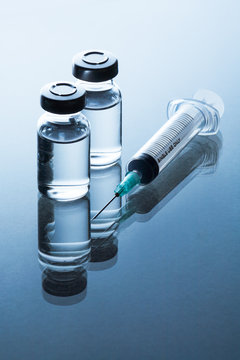 medical ampoules and syringe on blue background.