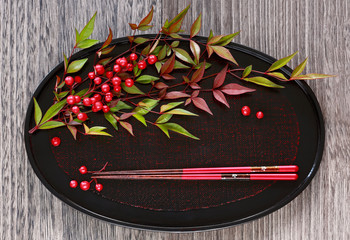 Red berries Sacred bamboo (Nandina Domestica) and chopsticks on Japanese tray.