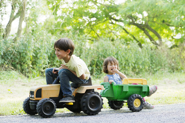 Young brother and sister riding on toy tractor